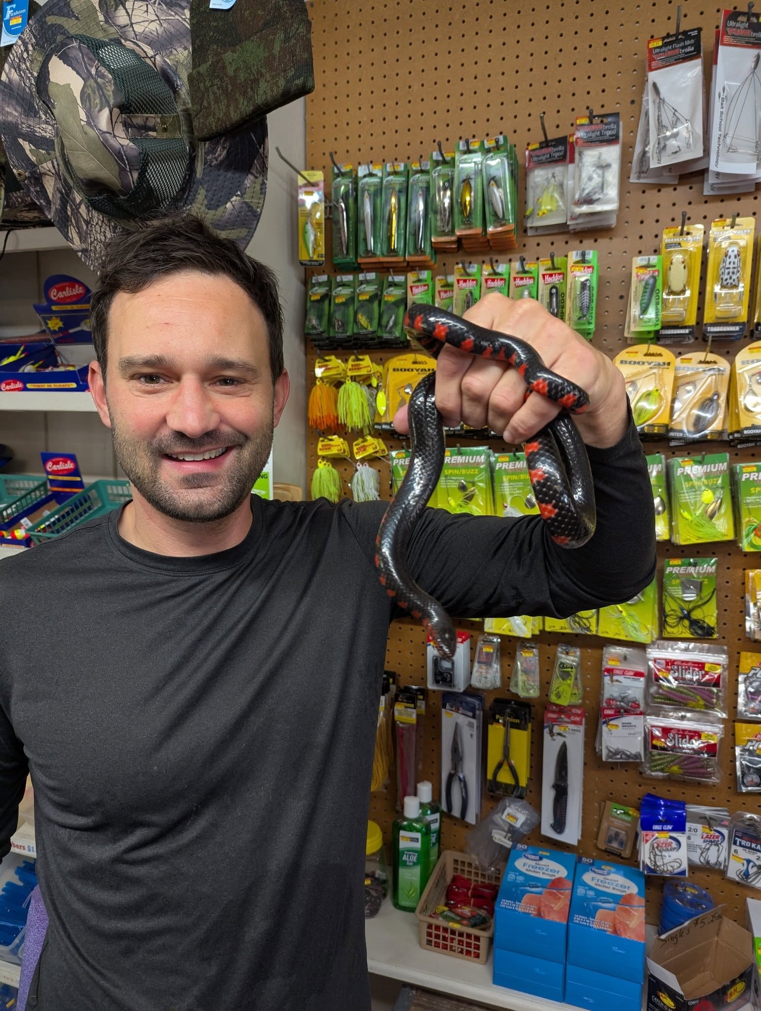 Staff member smiling with snake in front of the tackle wall