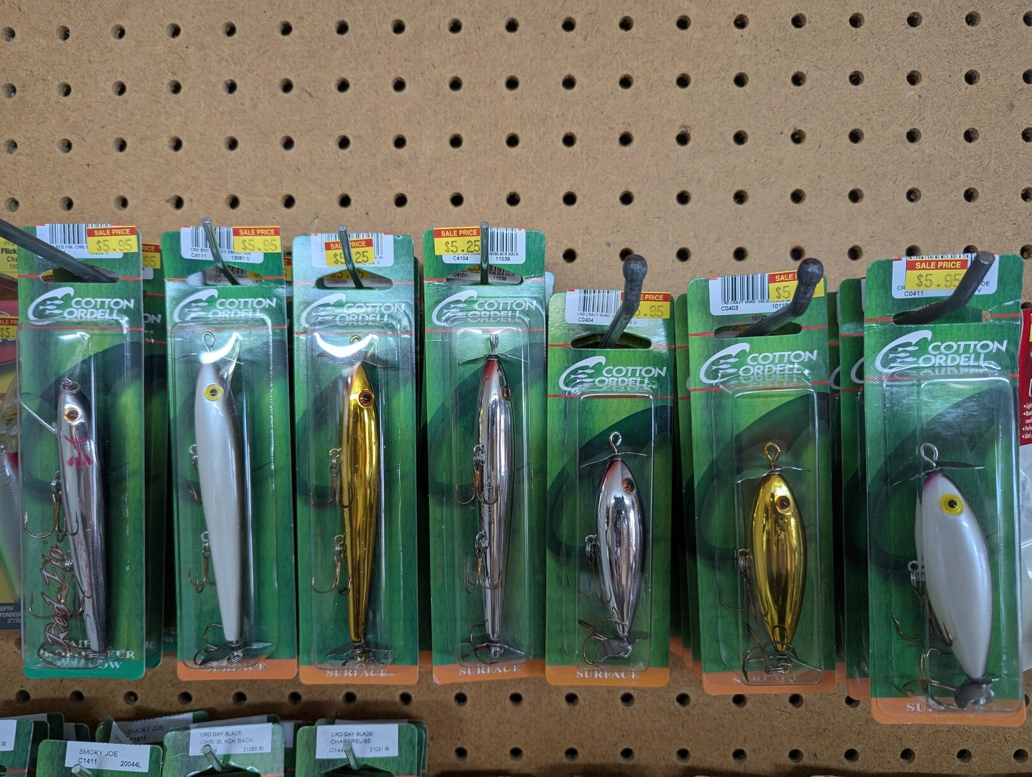 Cotton Cordell surface lures in silver and gold on the pegboard wall