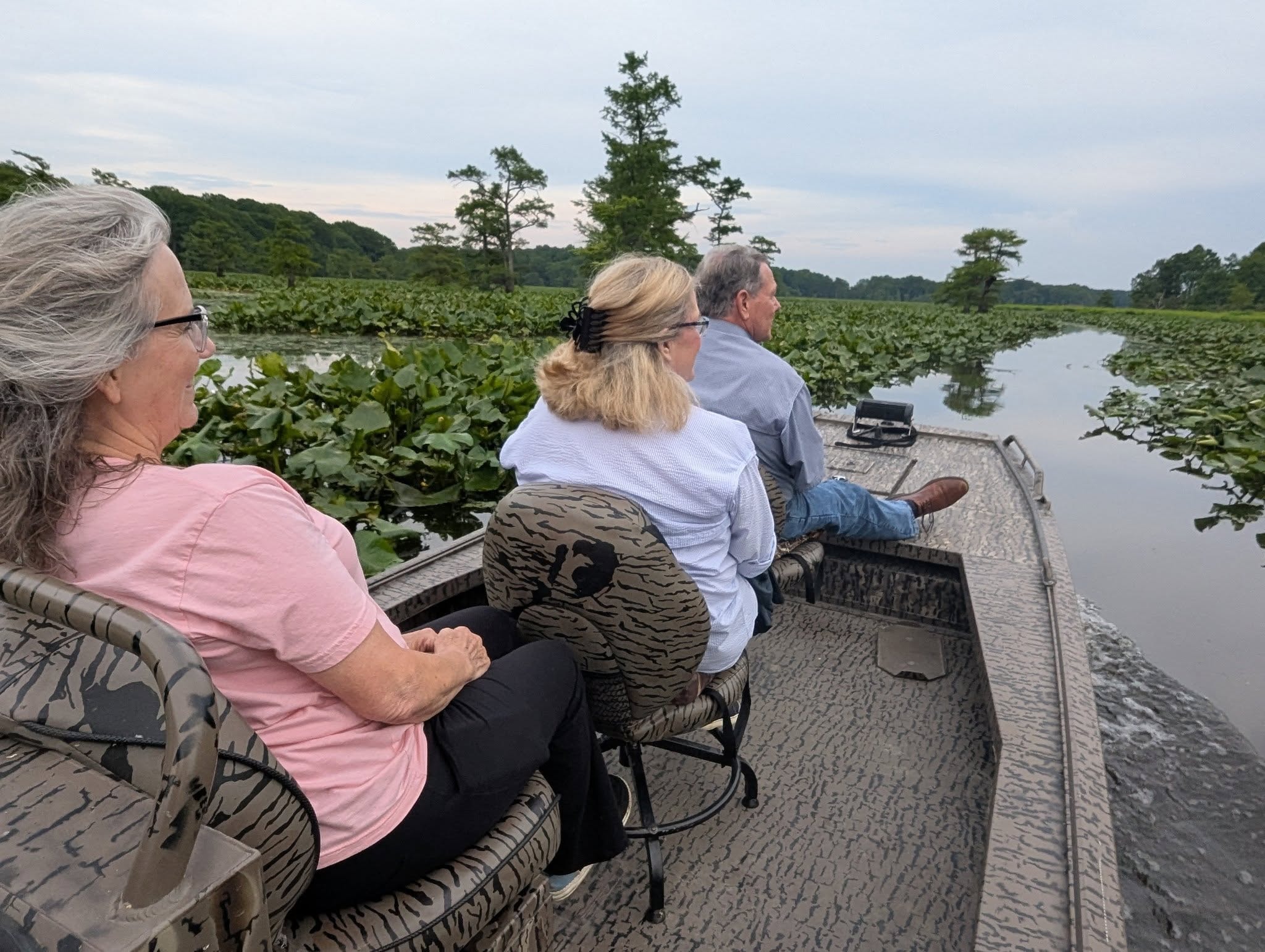 Three guests cruising through the lotus fields on a Reelfoot Lake boat tour