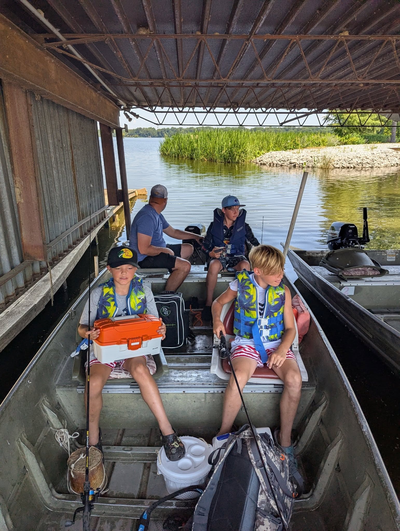 Kids and family ready to fish from a jon boat under the covered dock