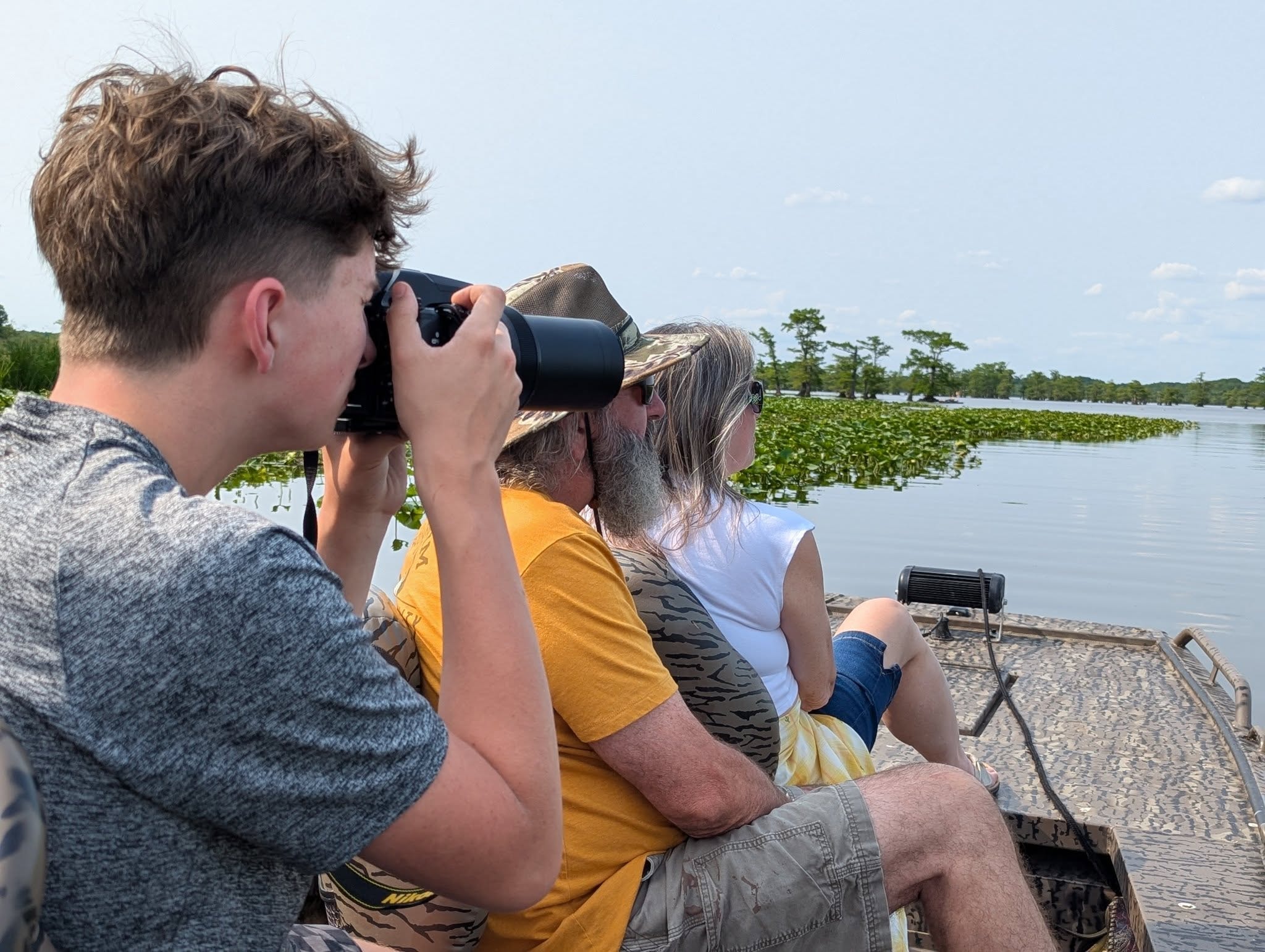 Guests using binoculars and a camera to spot wildlife on a Reelfoot Lake tour