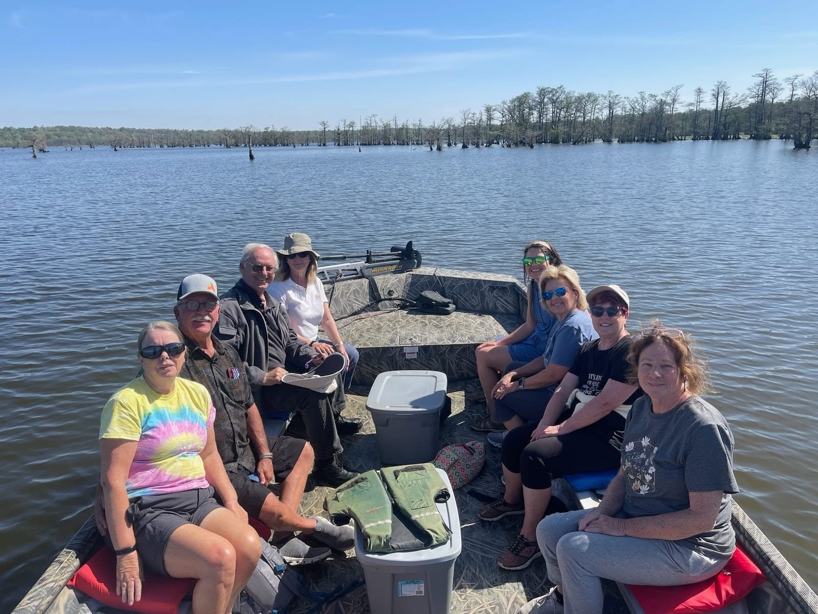Group of guests on a jon boat tour with cypress trees in the background on Reelfoot Lake