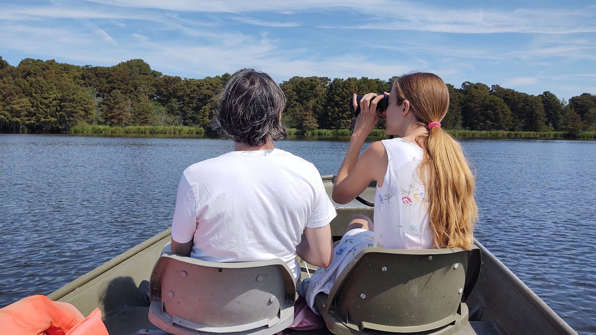 Two guests using binoculars to spot wildlife on a Reelfoot Lake boat tour