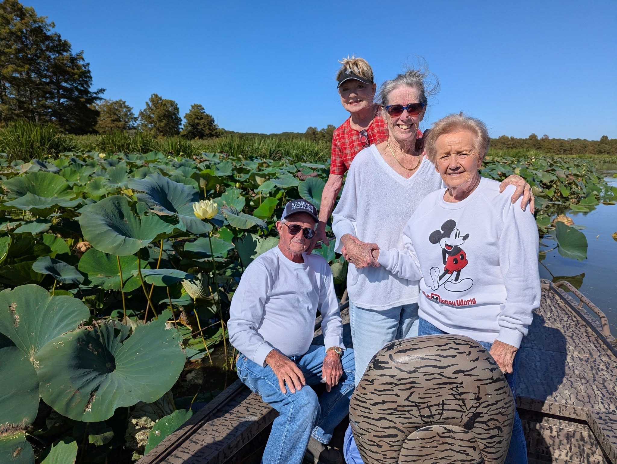 Group of guests smiling surrounded by lotus blooms on Reelfoot Lake