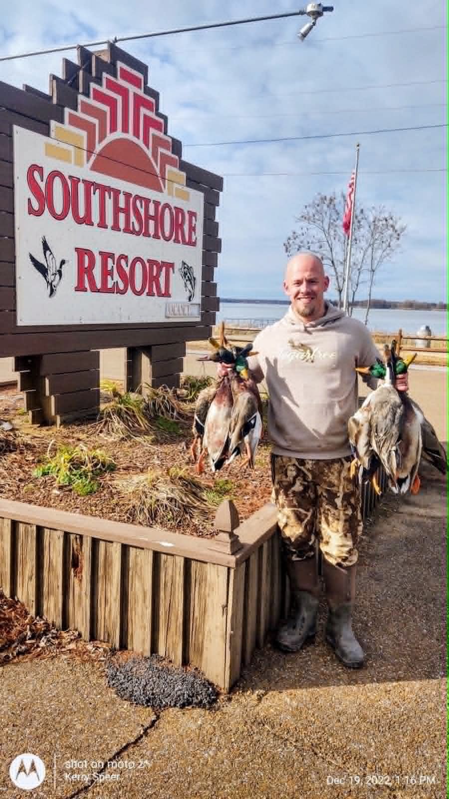 Hunter with mallard catch in front of Southshore Resort sign