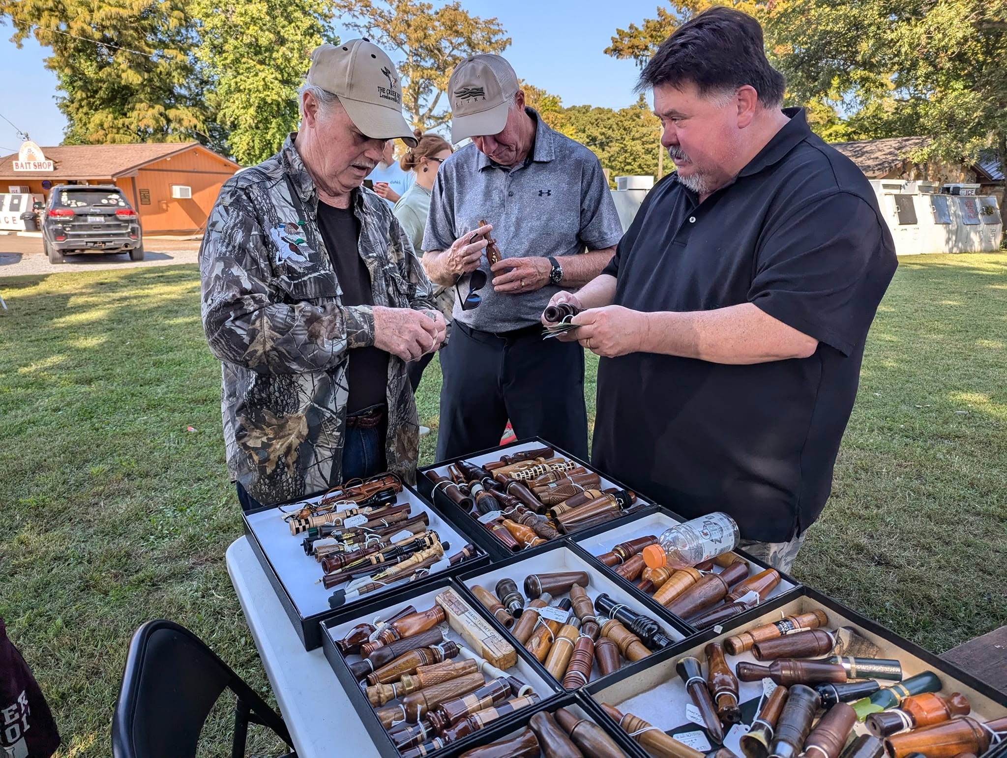 Three men examining duck calls at the Callmakers festival