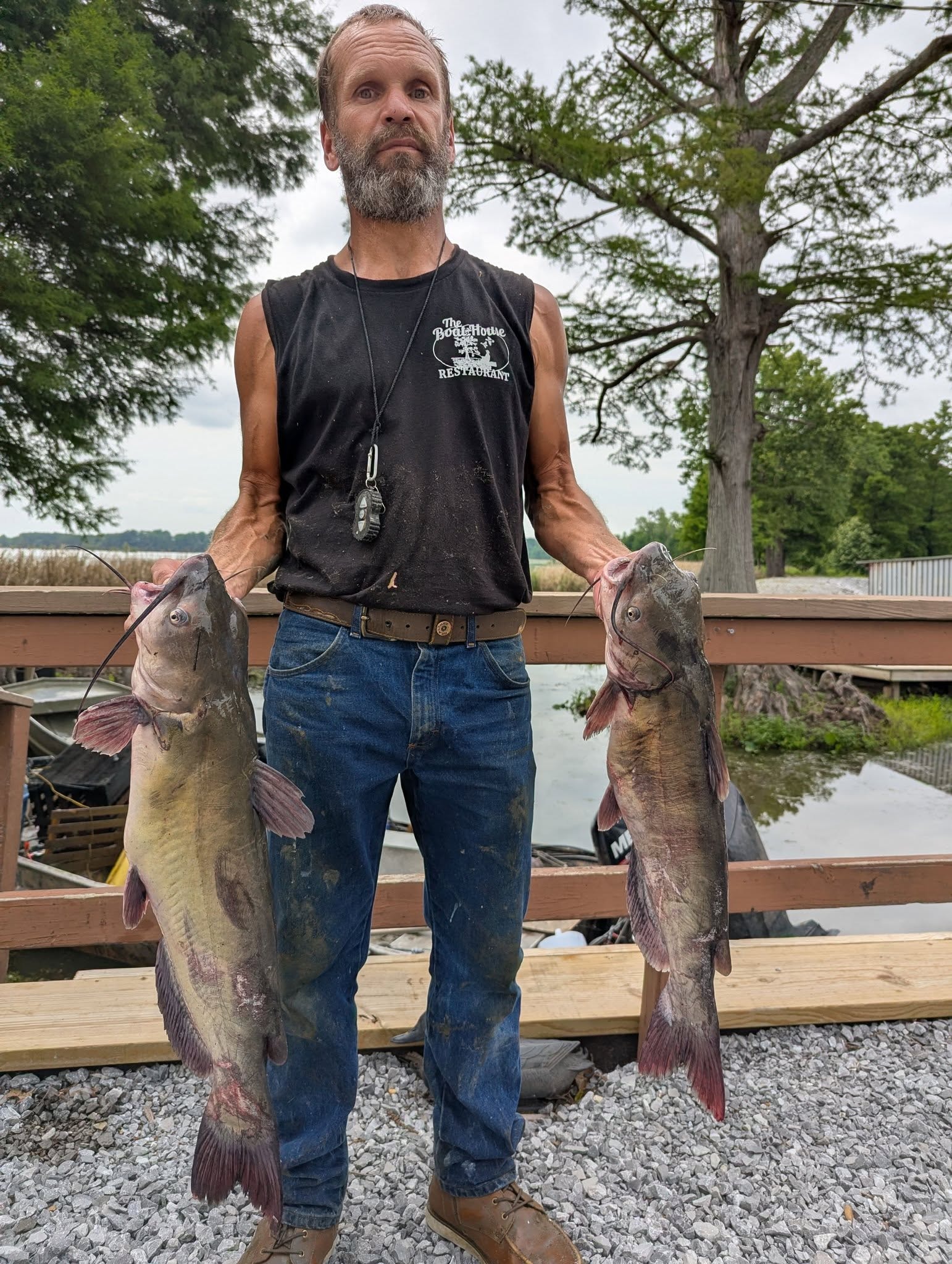 Angler holding two big catfish at the dock