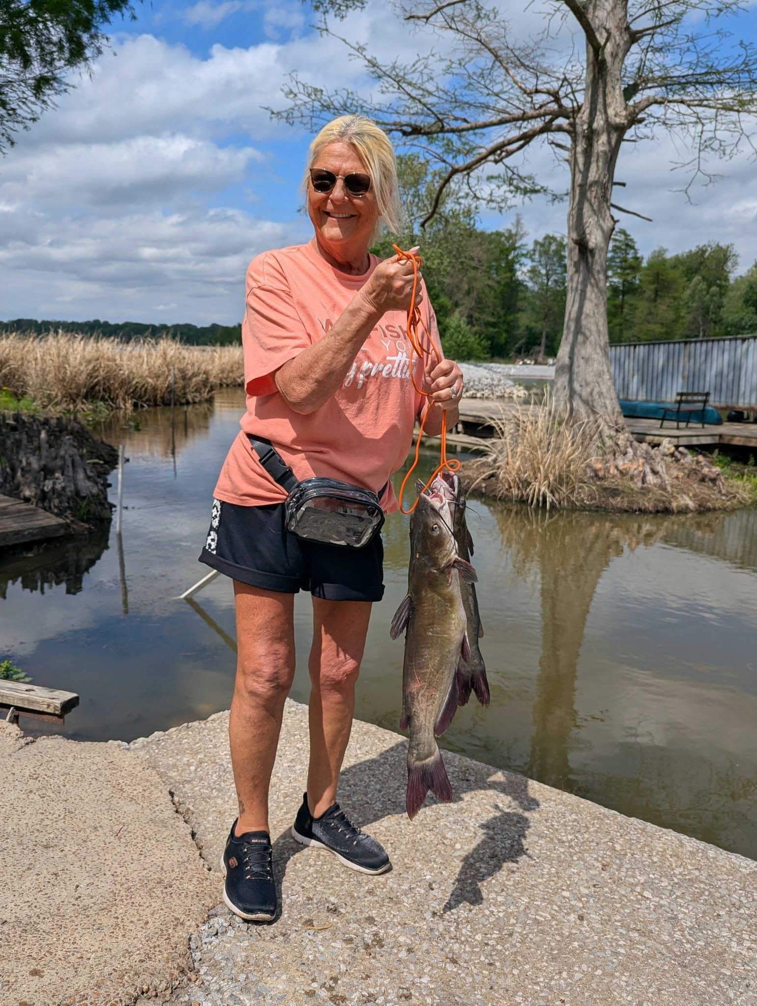Woman holding a big catfish by the cypress trees at Reelfoot Lake