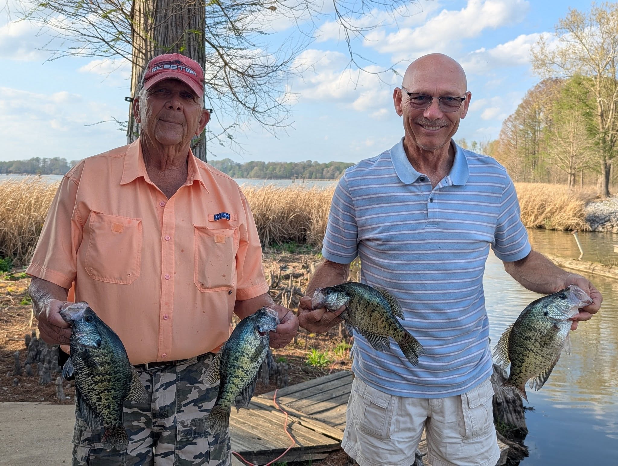 Two anglers holding crappie by the lake at Reelfoot