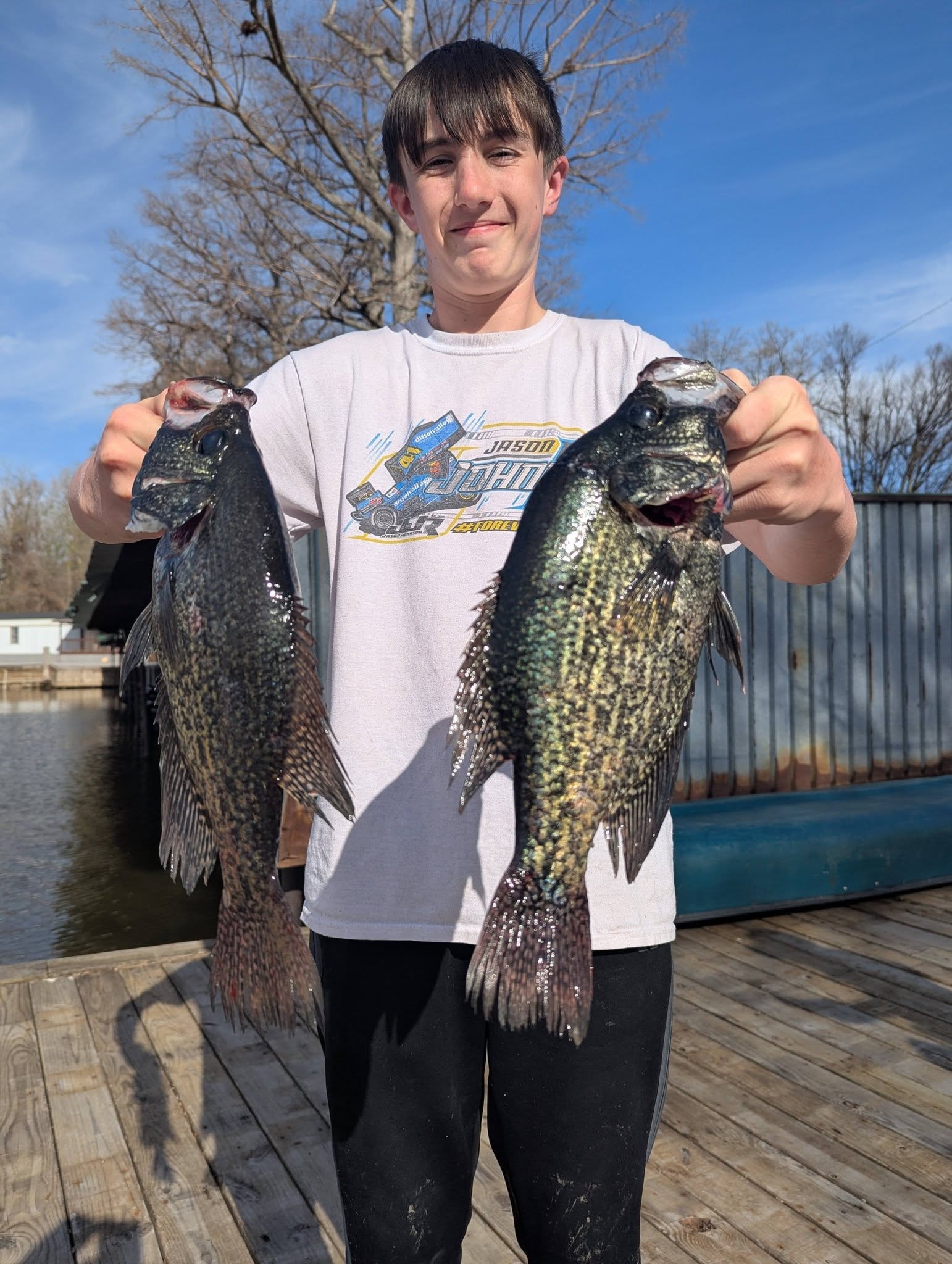 Teen angler holding two big crappie on the dock