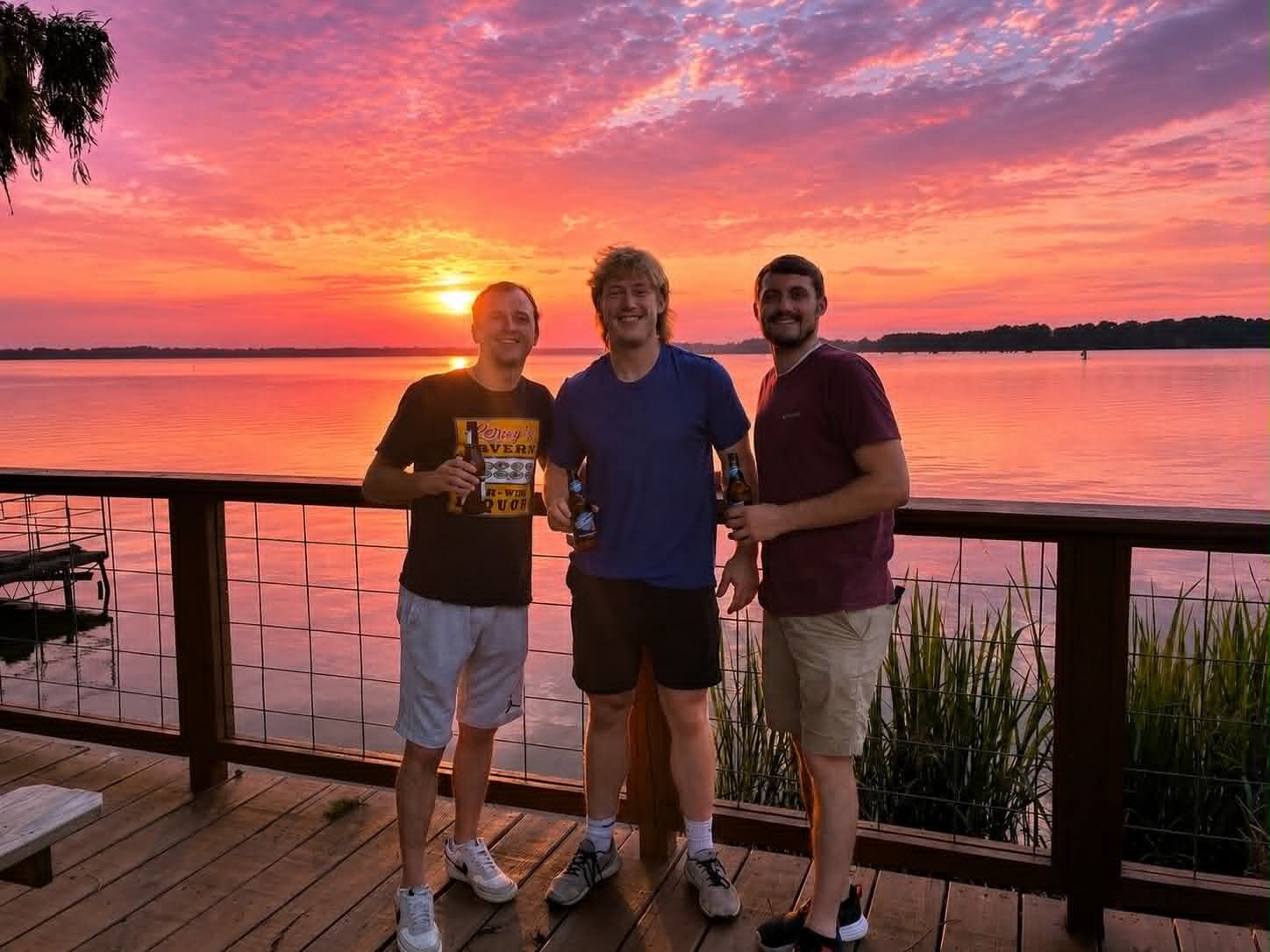 Three young men toasting on the Boat House Restaurant deck under a brilliant Reelfoot Lake sunset