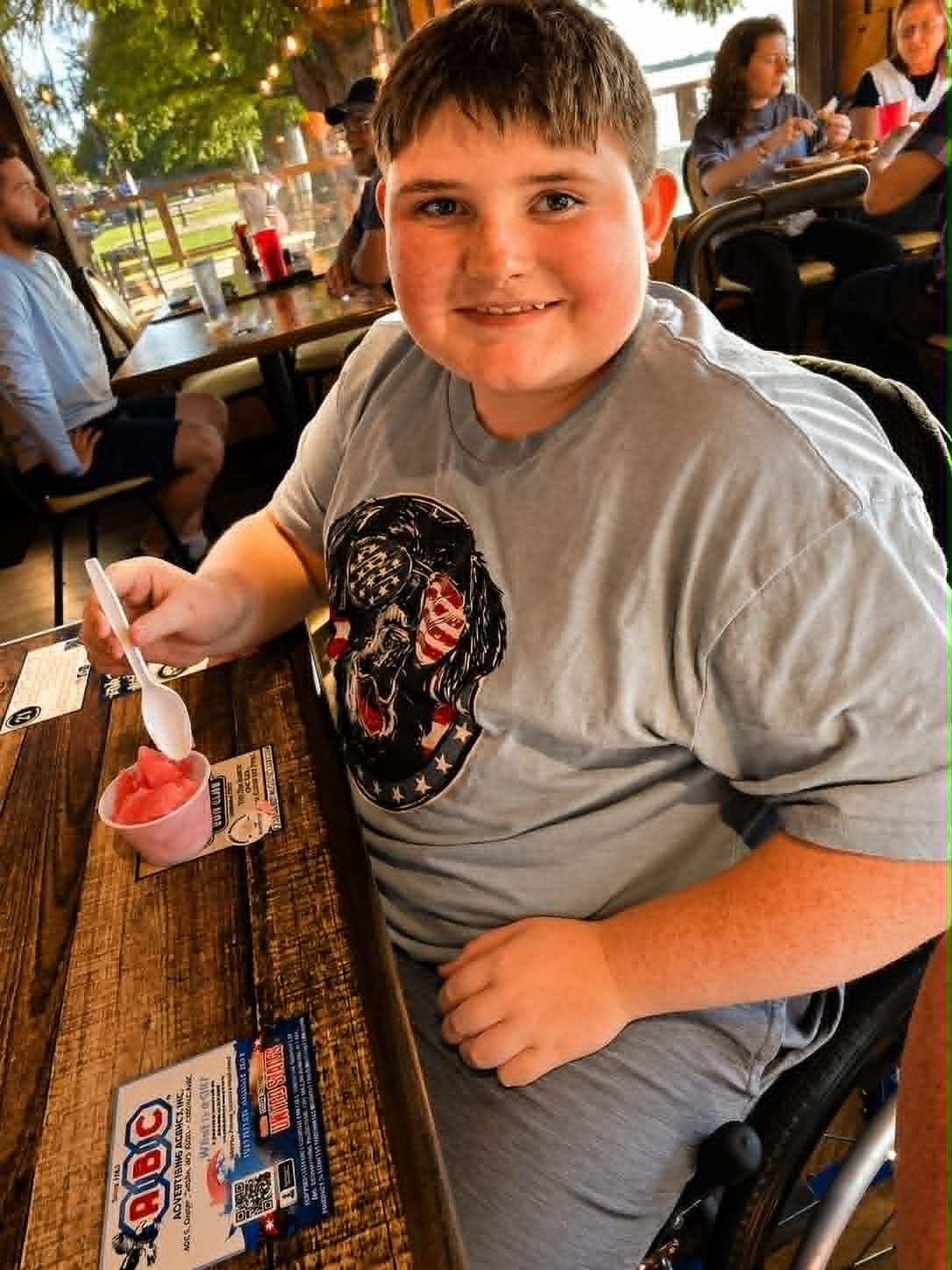 Young boy enjoying sherbet at The Boat House Restaurant with lake views behind him