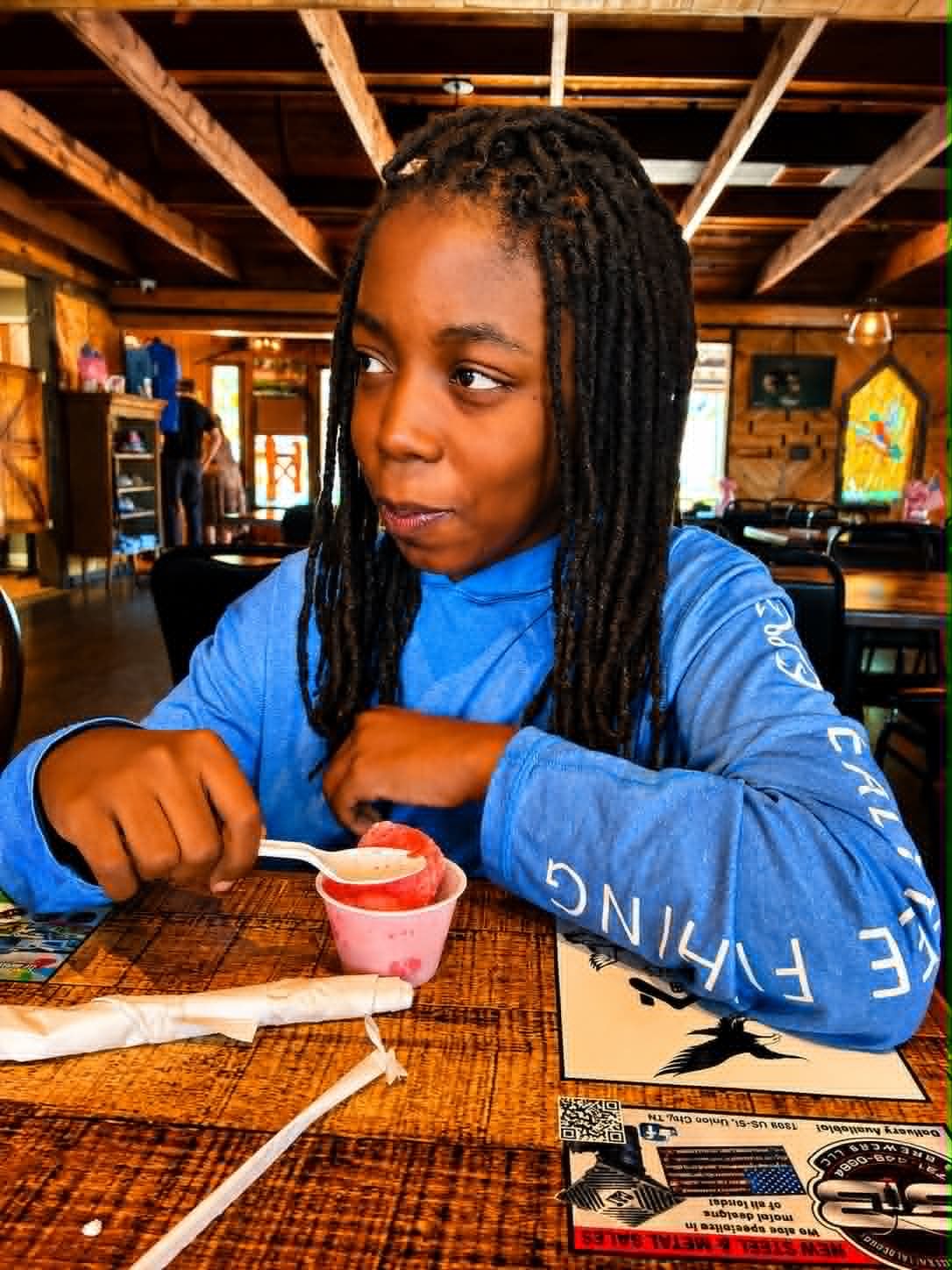 Young girl enjoying sherbet at The Boat House Restaurant with stained glass and welcome sign