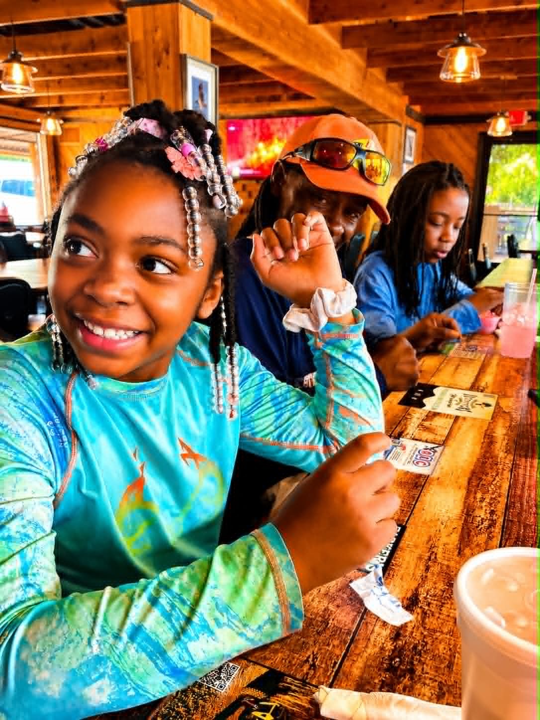 Three kids dining together at The Boat House Restaurant wooden interior with pink lemonade