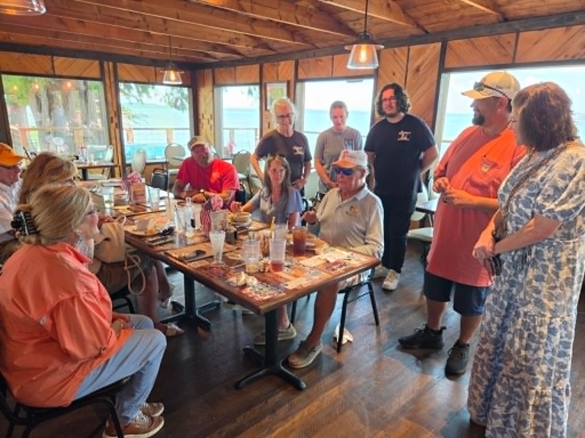 Large group of guests gathered around tables at The Boat House Restaurant with lake views