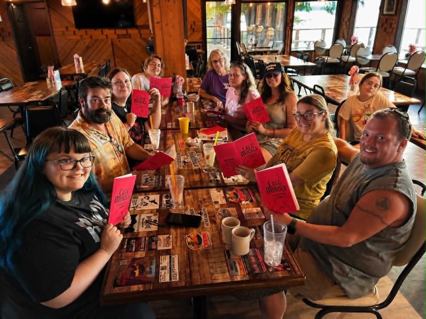 Large group of guests holding Cafe Murder mystery booklets at The Boat House Restaurant