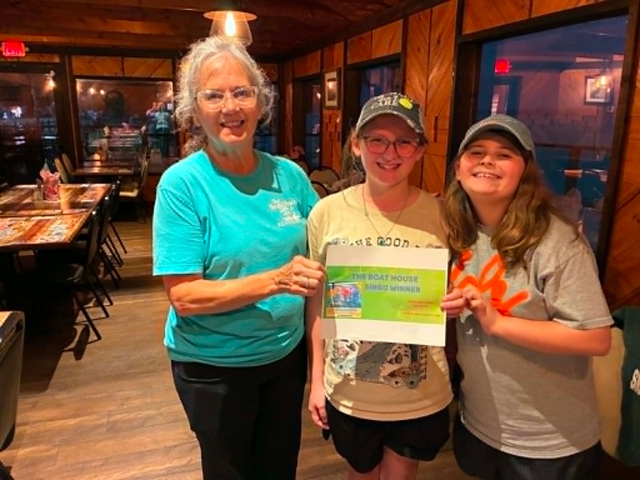 Staff member presenting Boat House Bingo winner certificate to two young girls