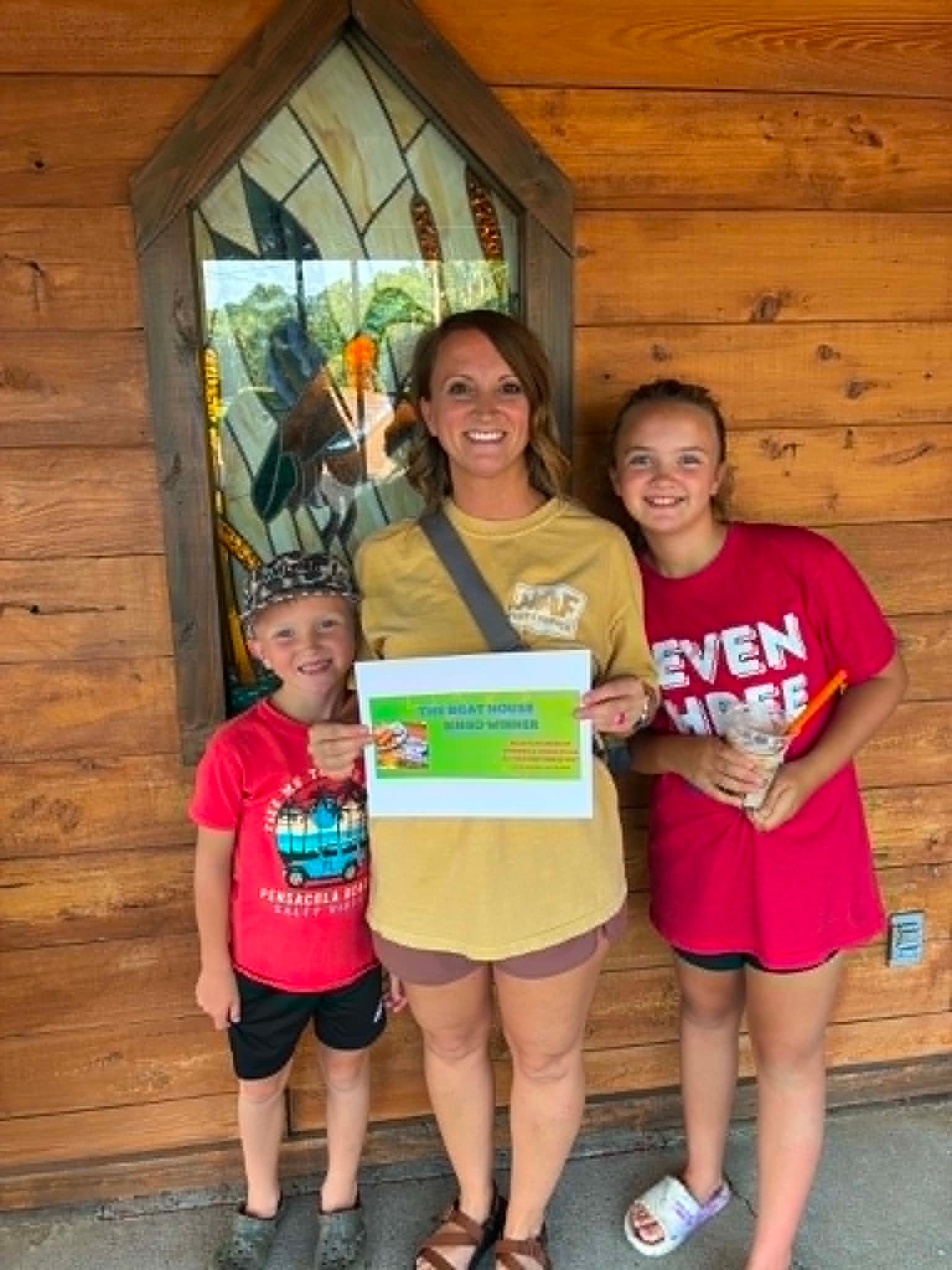 Mom and two kids holding a Boat House Bingo winner certificate at the restaurant entrance