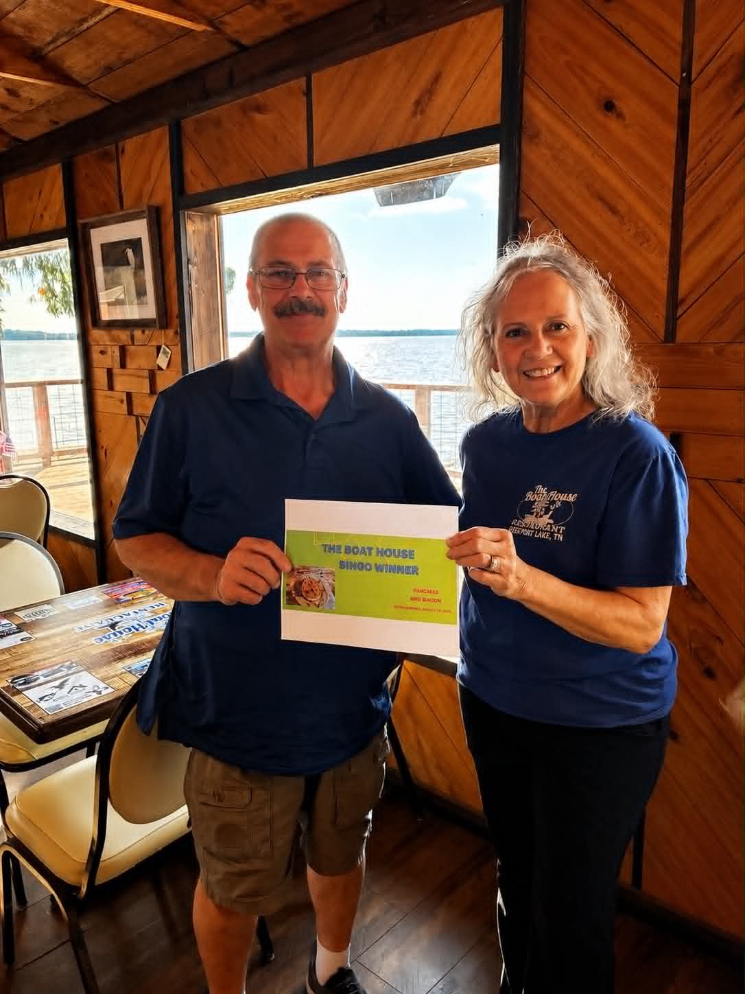 Boat House Bingo winner holding certificate with staff member at The Boat House Restaurant