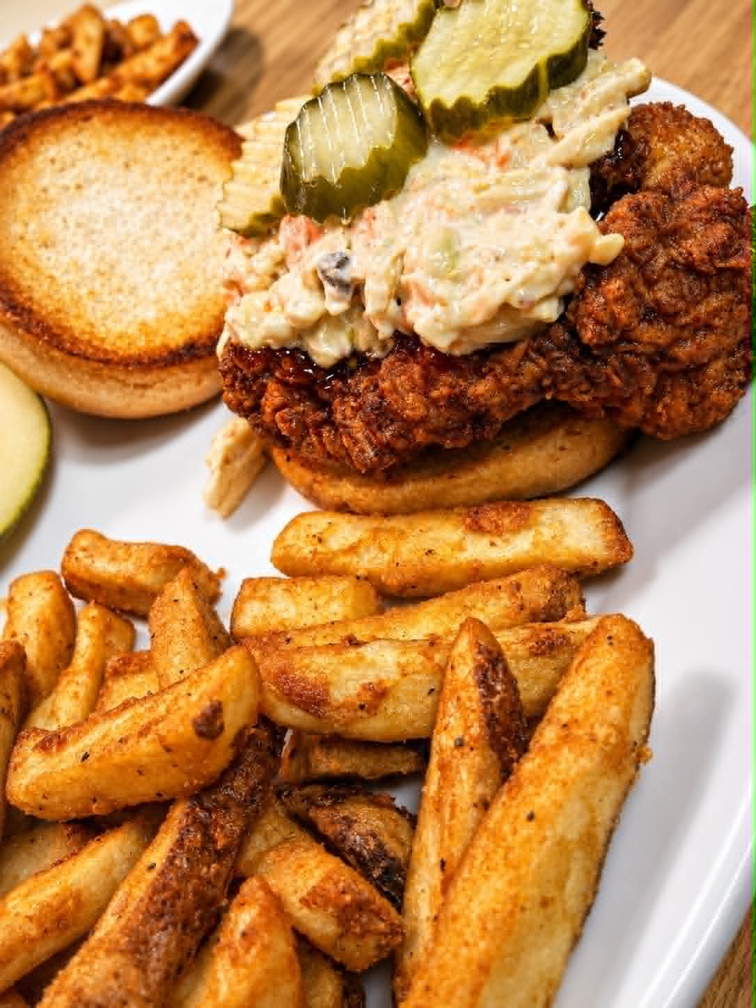 Crispy fried chicken sandwich with coleslaw, pickles and seasoned fries at The Boat House Restaurant