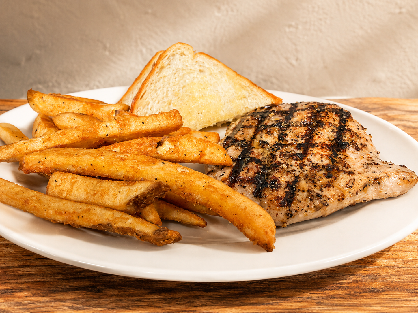 Grilled chicken breast with seasoned fries and toast at The Boat House Restaurant