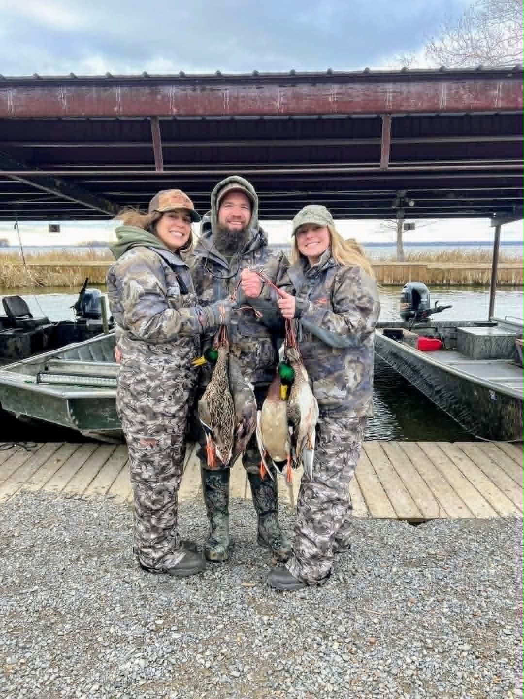 Three hunters displaying caught ducks