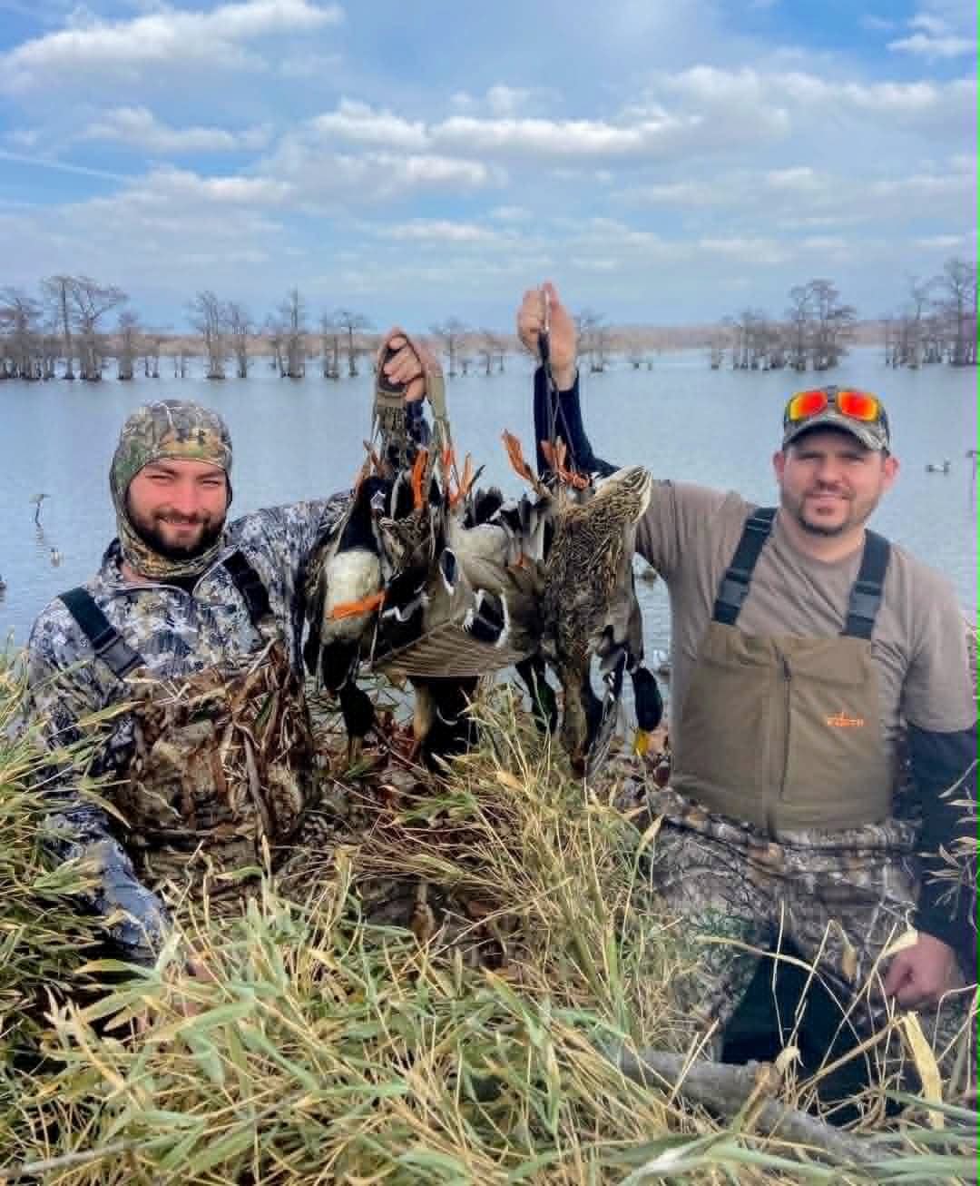 Hunters displaying duck catch on wetland